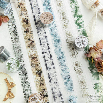 A close-up of vintage-inspired washi tape with floral, film strip, and snowflake designs arranged artistically on a white surface.