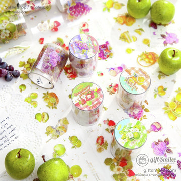 Vibrant fruit-themed washi tape rolls with apples, grapes, and floral designs displayed with green apples.