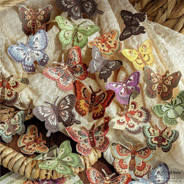A spread of colorful butterfly paper cutouts on a rustic fabric background, perfect for nature-themed scrapbooking