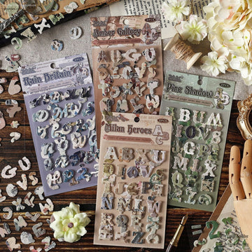 A beautifully arranged set of vintage alphabet scrapbook stickers in four unique designs, styled with flowers and craft tools
