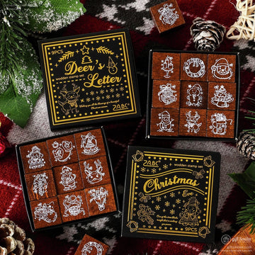 Wooden Christmas stamp set with 9 festive designs and black and gold packaging