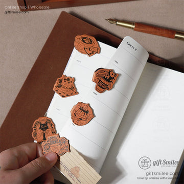 A planner with vintage-style magnetic bookmarks featuring cat and tea designs attached to its pages.