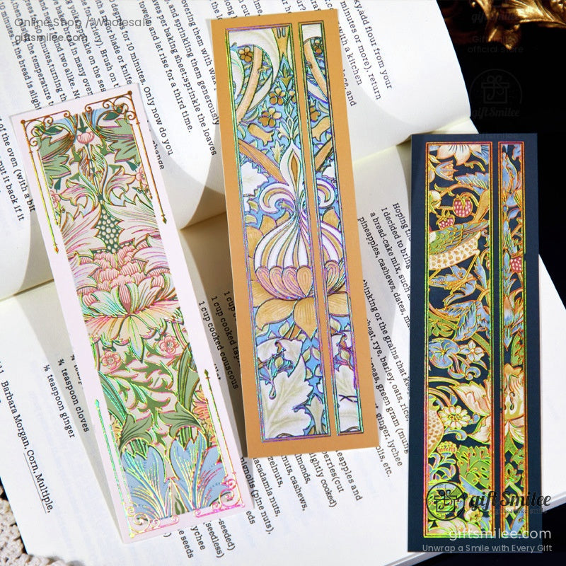 Three elegant holographic floral bookmarks resting on an open book, showcasing their luminous details