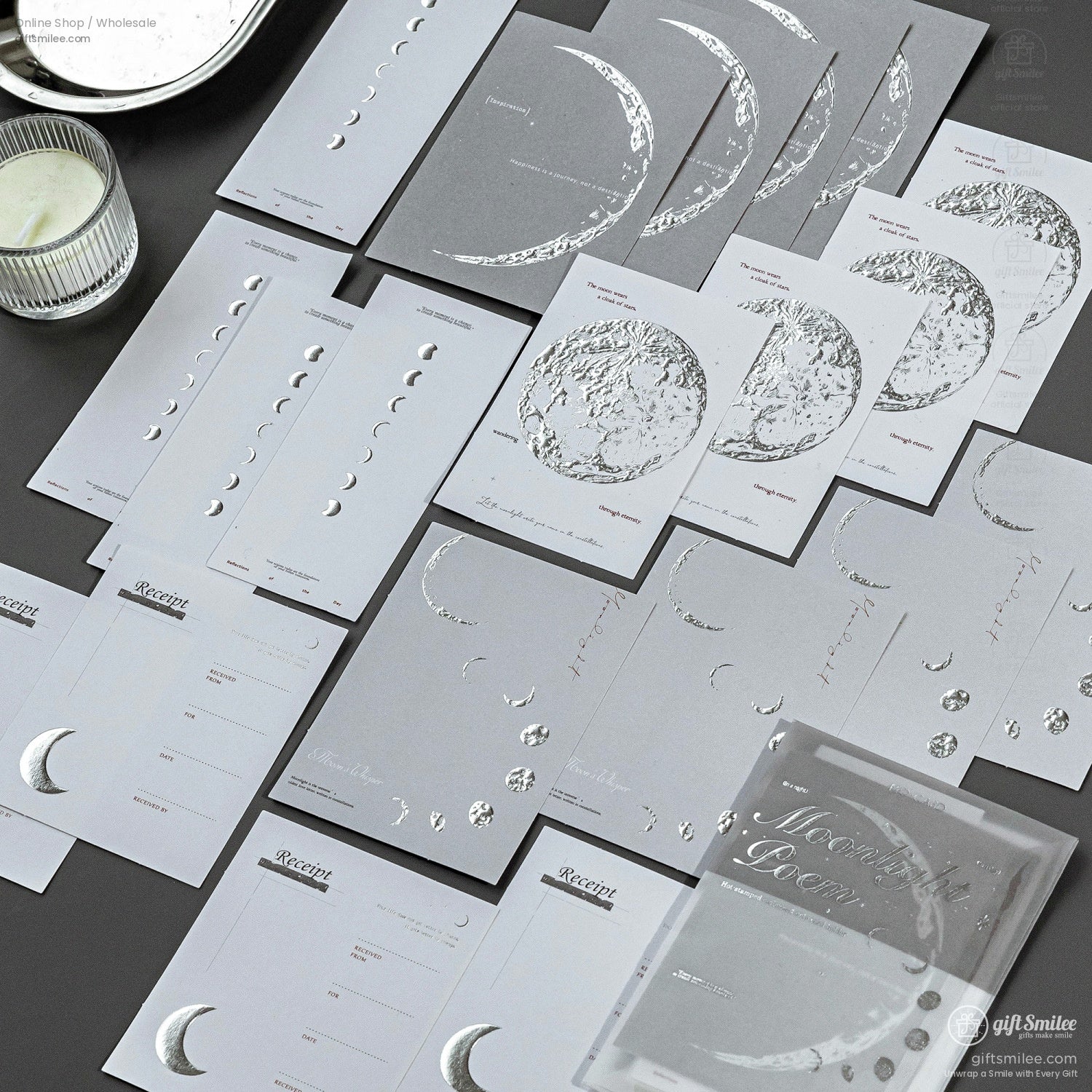 A collection of moon phase-themed silver foil stationery cards displayed neatly on a dark surface