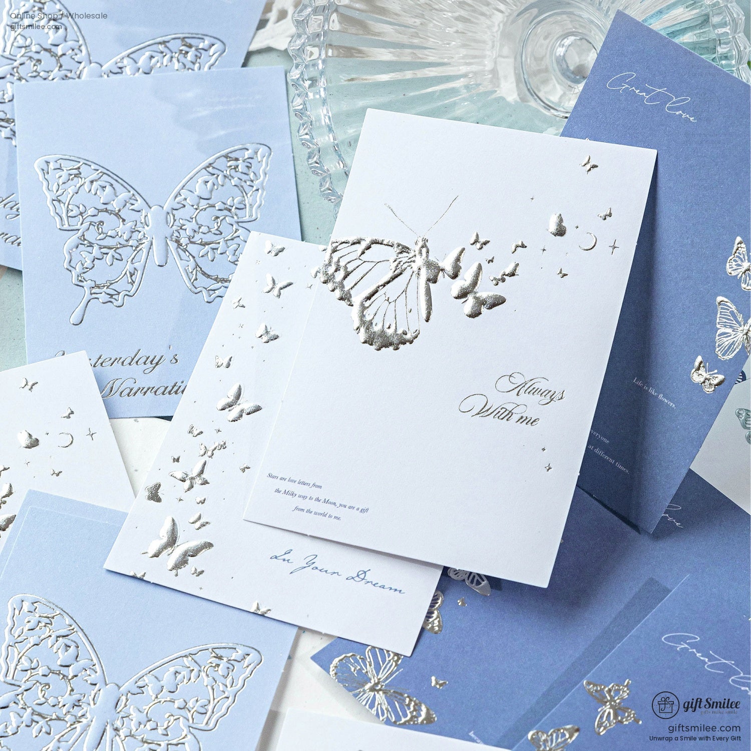 Butterfly-themed silver foil cards with intricate designs on a light blue background