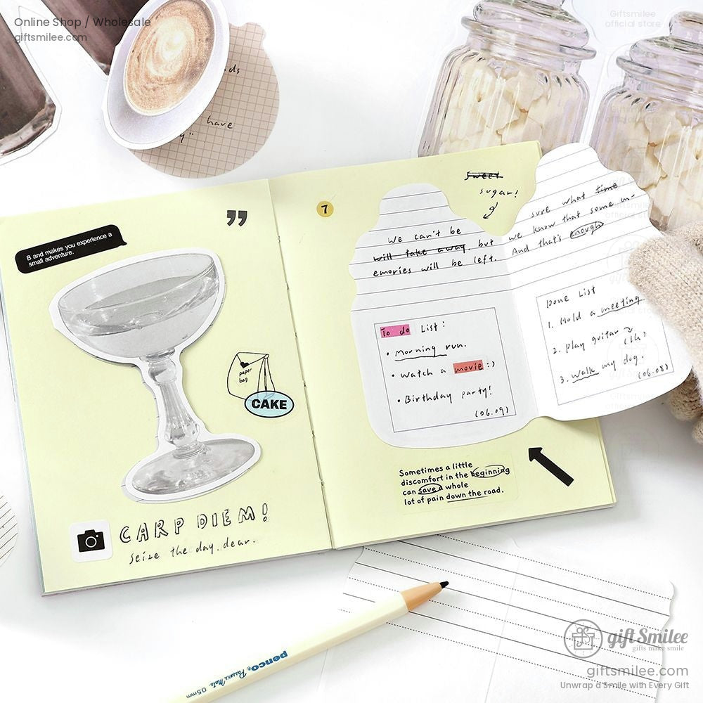 Open planner with food and glass stickers, including a latte design, alongside a pencil and written lists