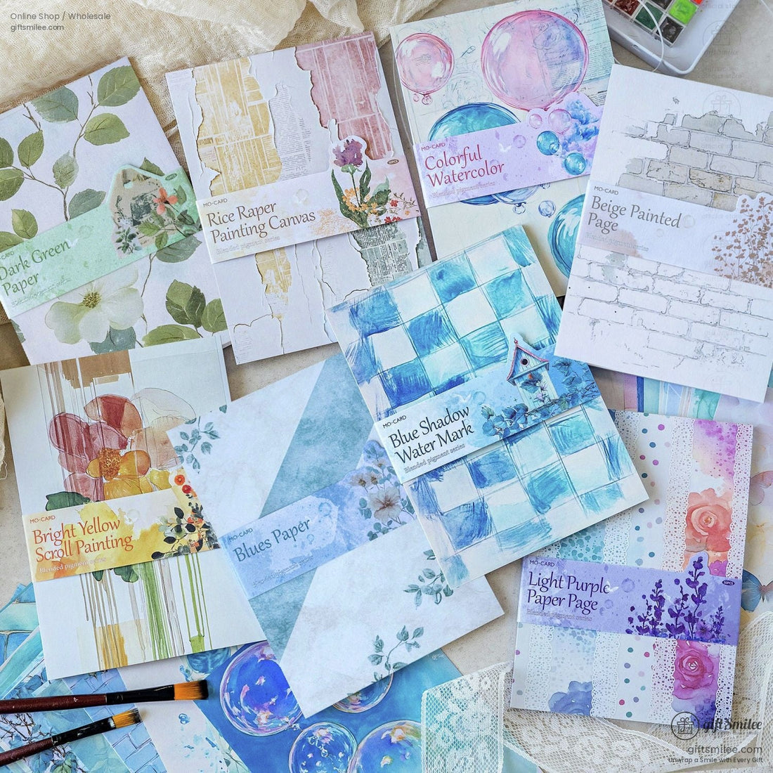 A colorful display of watercolor-themed scrapbook papers with floral and abstract designs