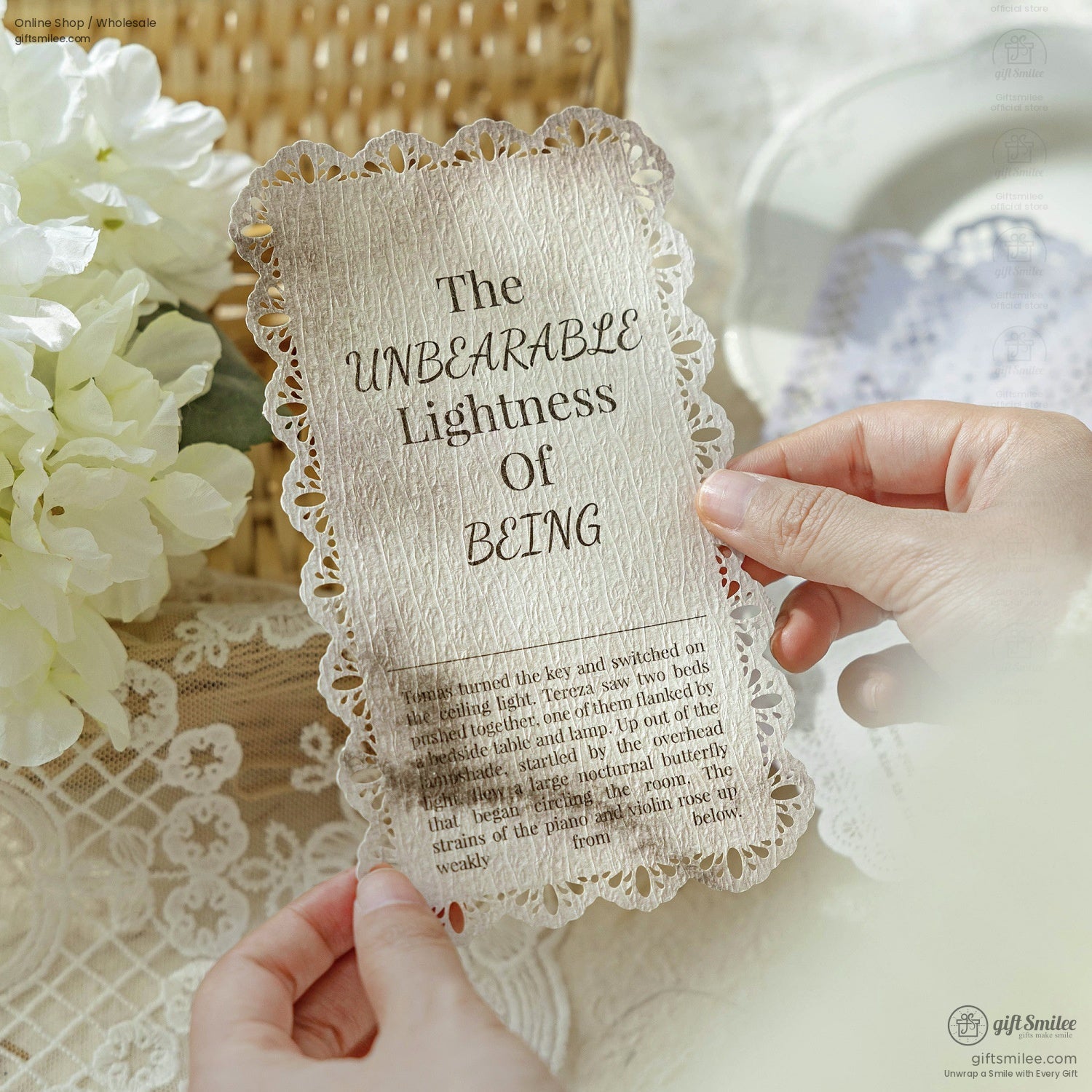 Close-up of a vintage-style card titled The Unbearable Lightness of Being held by hands with lace decor
