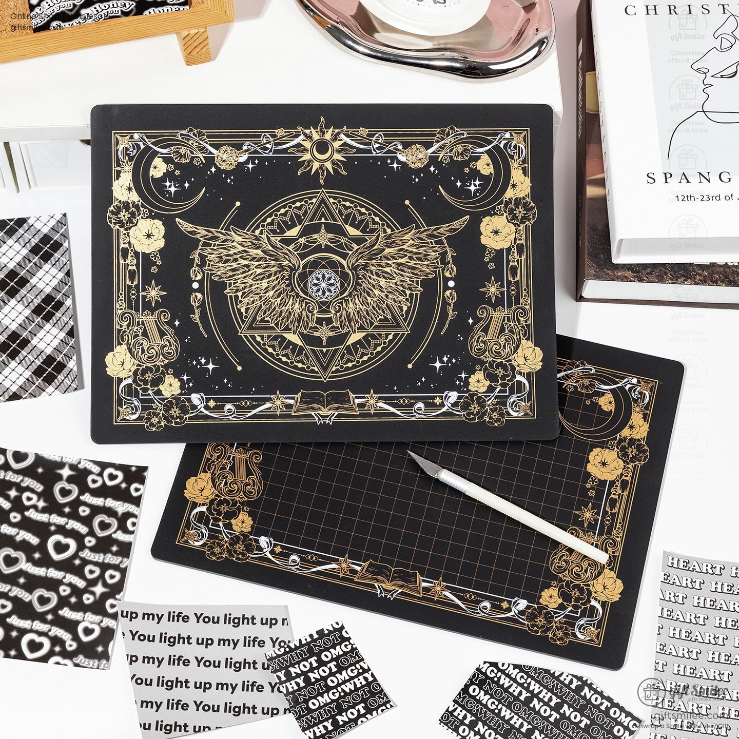Black and gold celestial-themed cutting mat with intricate wing and moon design.