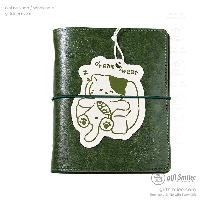 Close-up of green leather journal with adorable sleeping cat tag