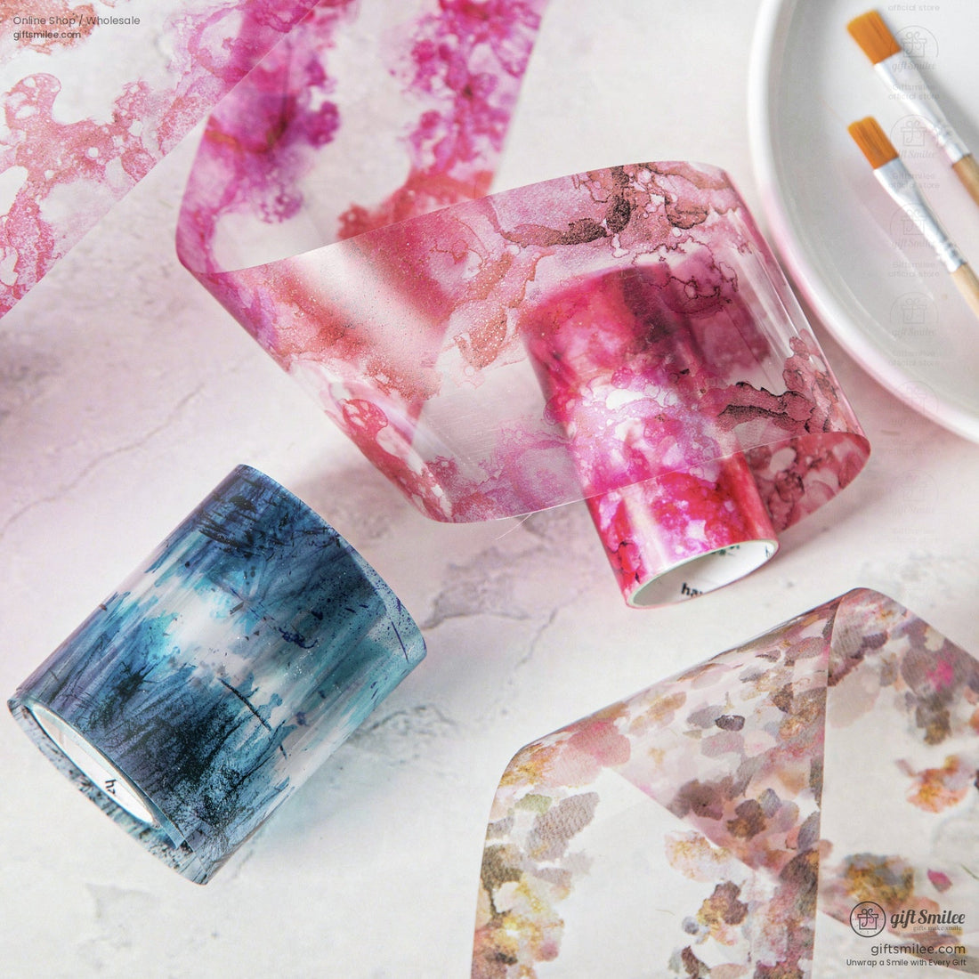 Close-up of watercolor washi tape rolls in vibrant pink, blue, and floral patterns for arts and crafts.
