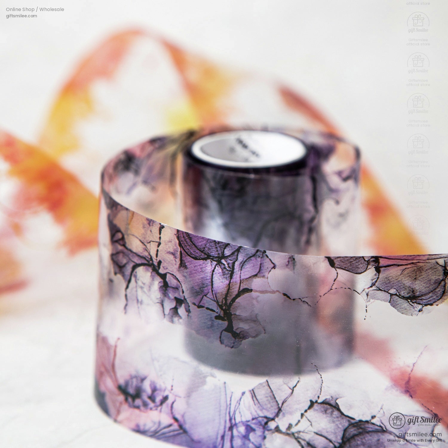 A roll of purple and orange floral watercolor washi tape unrolled on a clean surface.