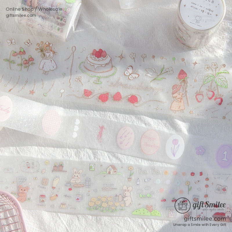A spread of strawberry, floral, and bunny PET washi tape on a white cloth background