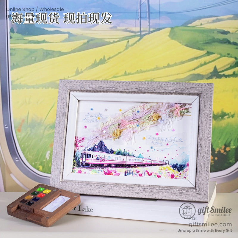A framed artwork featuring a train landscape, complemented by crafting supplies like watercolors