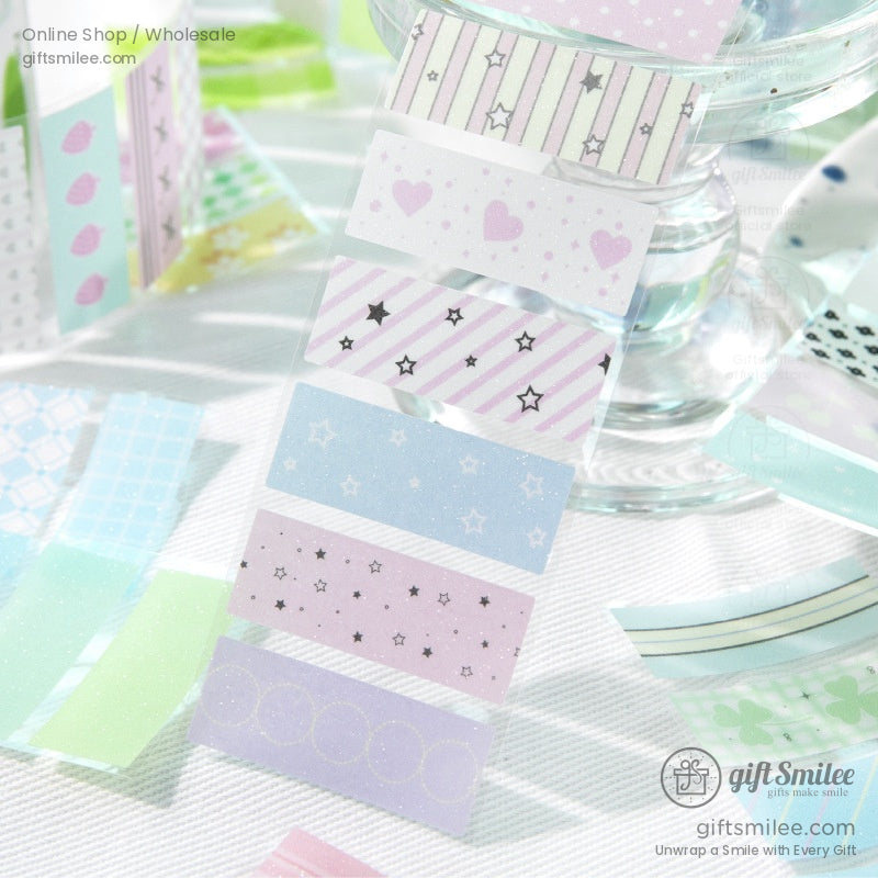 Decorative pastel washi tapes unrolled on a clear glass stand, showcasing their vivid patterns and colors