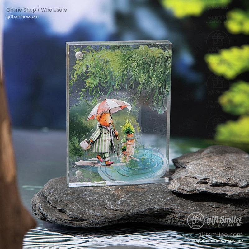 Acrylic art piece with a whimsical bear holding an umbrella, standing by a pond surrounded by greenery