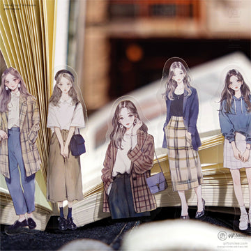 A set of fashion girl stickers standing on an open book, showcasing vintage-style clothing.