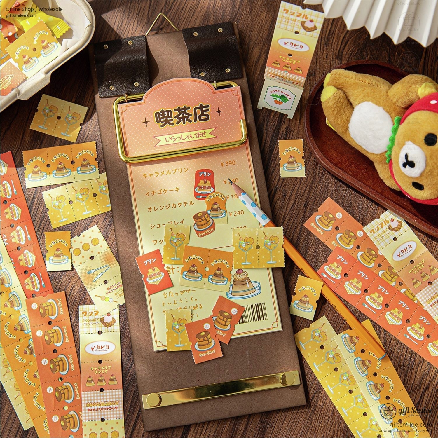 A display of orange and yellow cafe-themed stickers alongside a teddy bear plush and stationery items