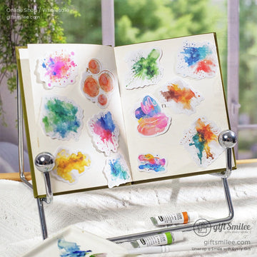 Vibrant watercolor splash stickers displayed on an open journal with natural light