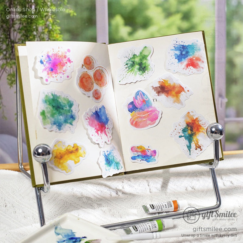 Vibrant watercolor splash stickers displayed on an open journal with natural light