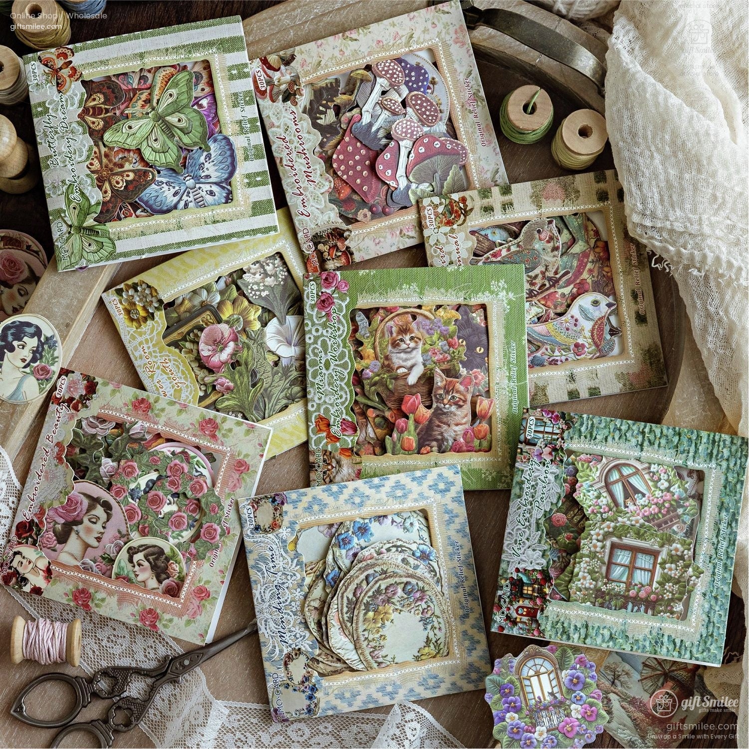 A collection of vintage-inspired ephemera packs featuring floral, butterfly, and whimsical designs on a wooden surface