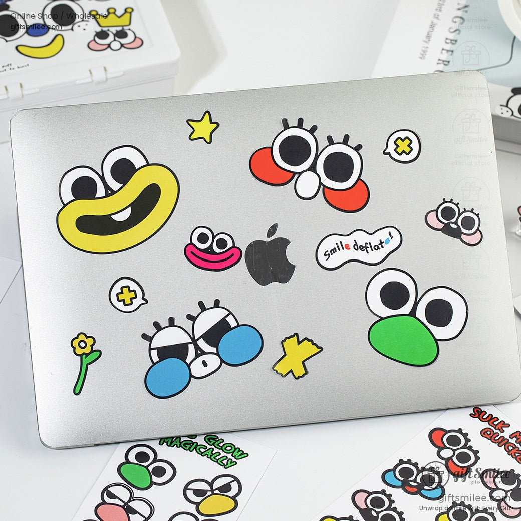 Cartoon face stickers decorating a silver laptop, showcasing creative uses for the stickers