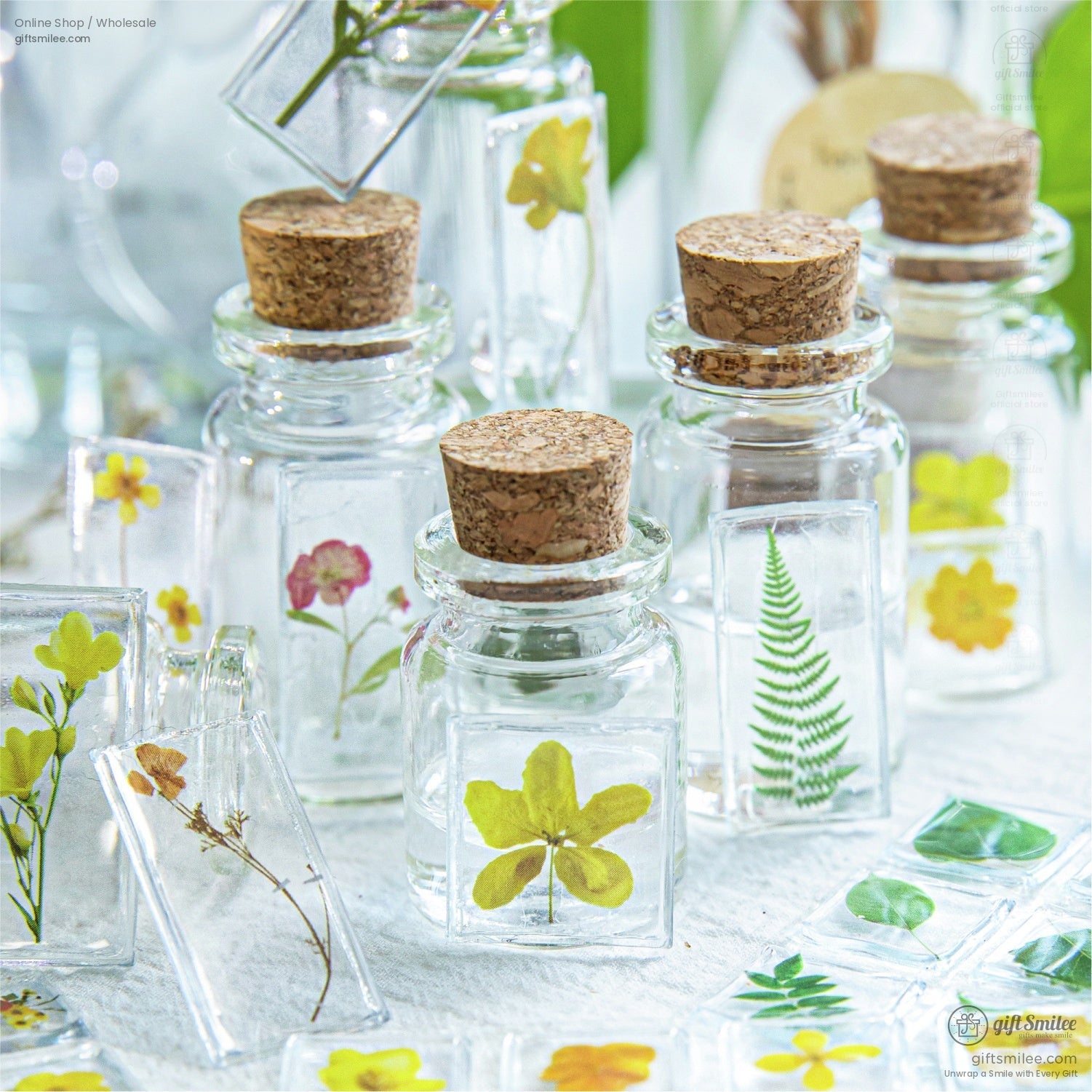 Miniature glass bottles filled with floral and leaf transparent stickers, arranged elegantly