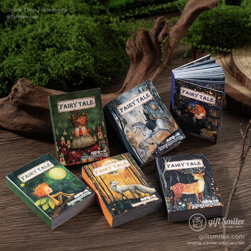 Set of six fairy tale mini notebooks with charming fantasy art, staged on a rustic wooden surface with moss accents