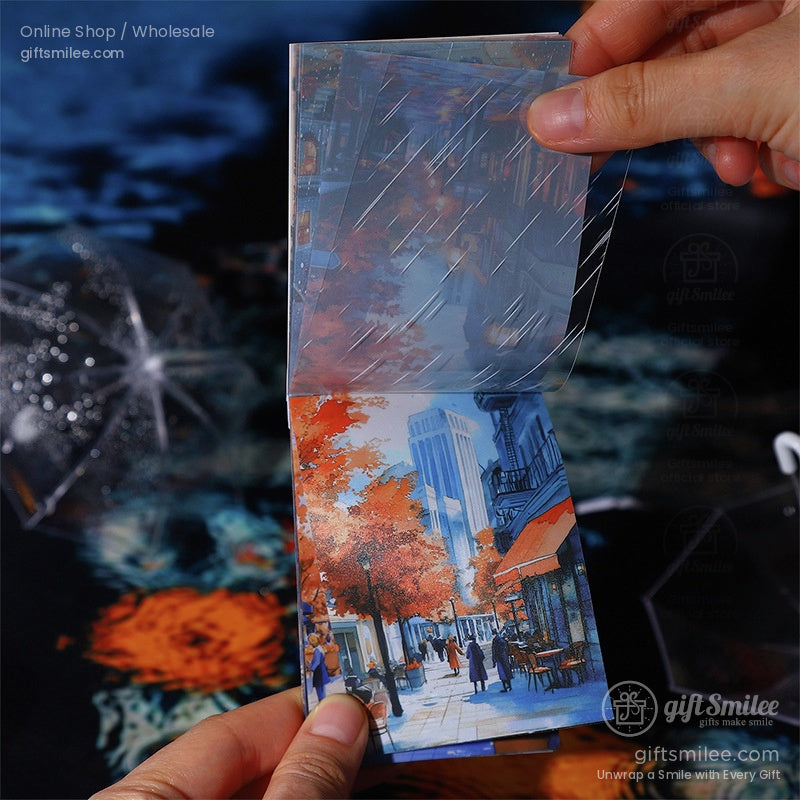 A hand holding a transparent overlay sticker with a fall-themed urban landscape