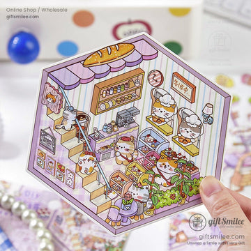 A close-up of a hexagonal cartoon sticker featuring a cute bakery scene with cats