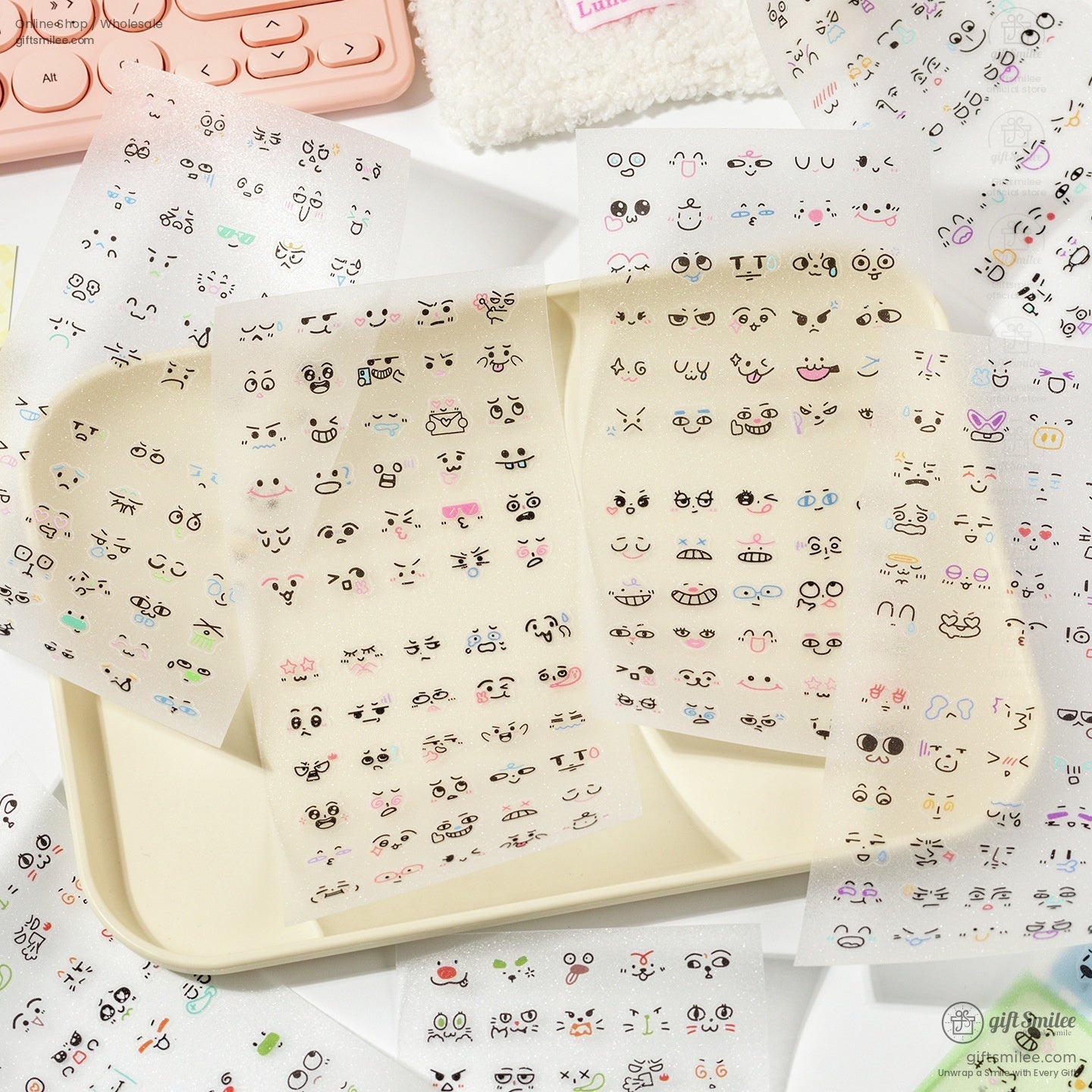 Multiple transparent sticker sheets with kawaii cartoon face expressions spread on a beige tray