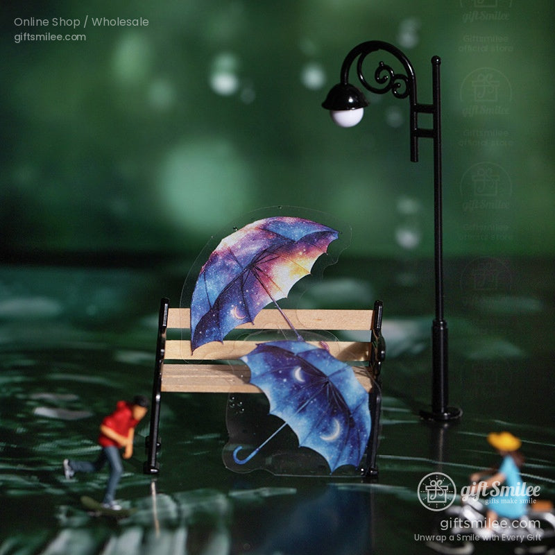 Two galaxy-themed umbrella stickers placed on a miniature park bench
