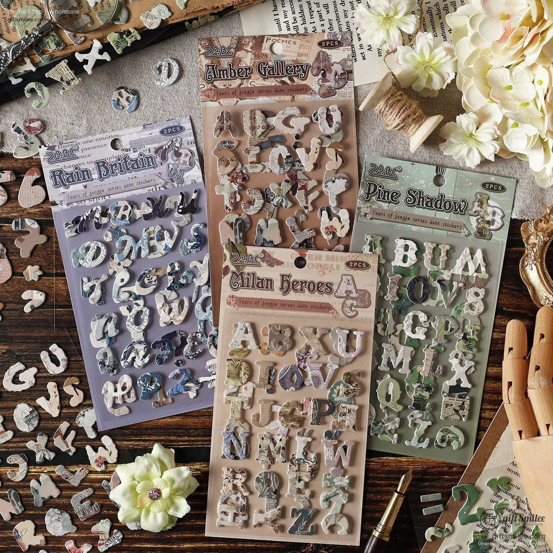 A beautifully arranged set of vintage alphabet scrapbook stickers in four unique designs, styled with flowers and craft tools