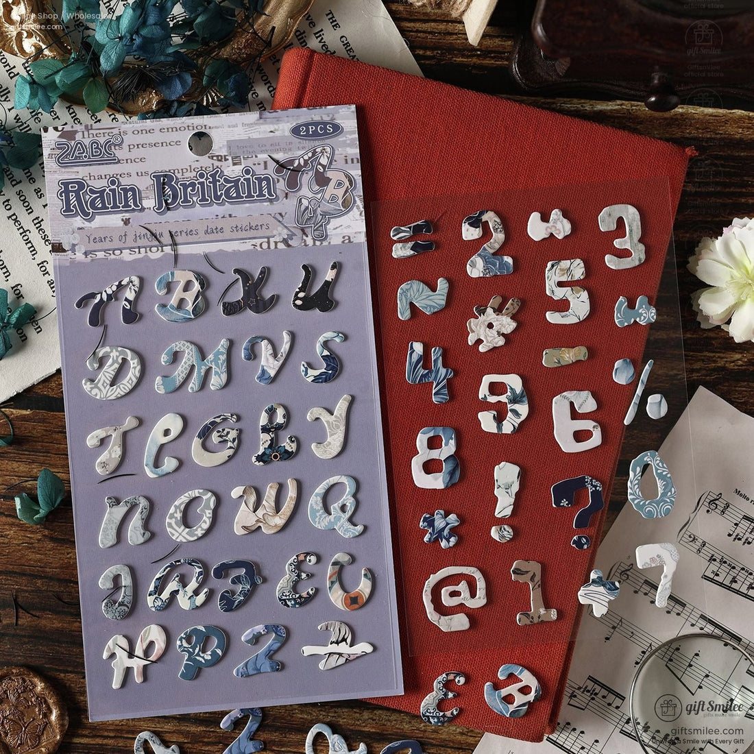 A beautifully arranged set of vintage alphabet scrapbook stickers in four unique designs, styled with flowers and craft tools