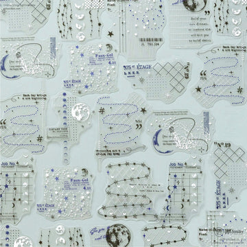 A flat lay of transparent celestial-themed stickers featuring stars, moons, and vintage text designs, perfect for scrapbooking or journaling