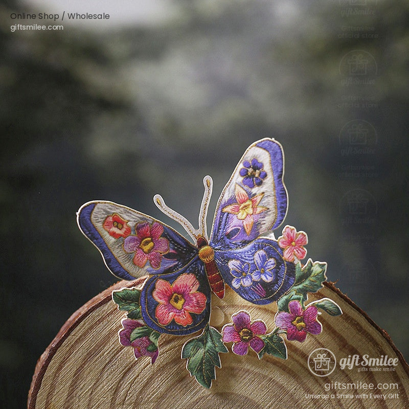 A set of embroidery stickers featuring flowers, butterflies, birds, and a honeybee displayed in a wooden hoop with a forest backdrop
