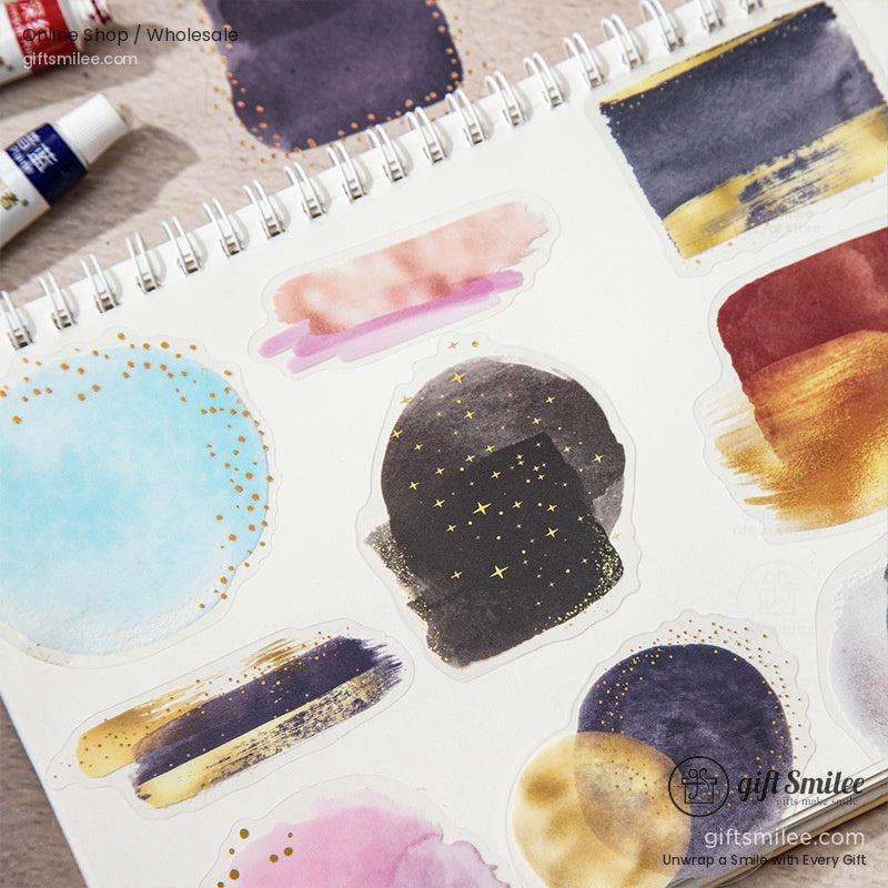 A set of abstract watercolor stickers with galaxy-inspired designs on a mini easel