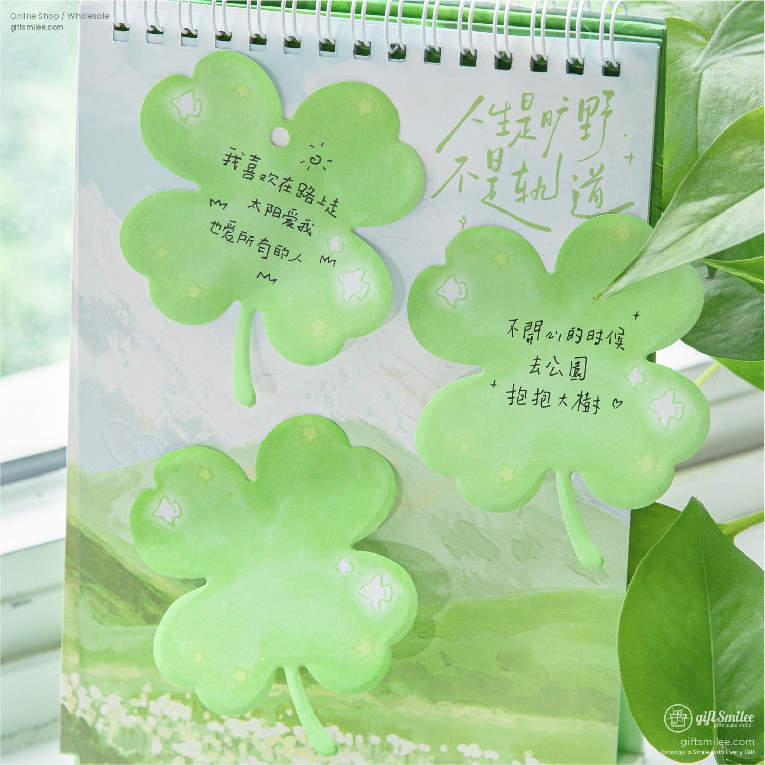 Green clover-shaped sticky notes displayed on a nature-themed notebook with inspiring handwritten messages