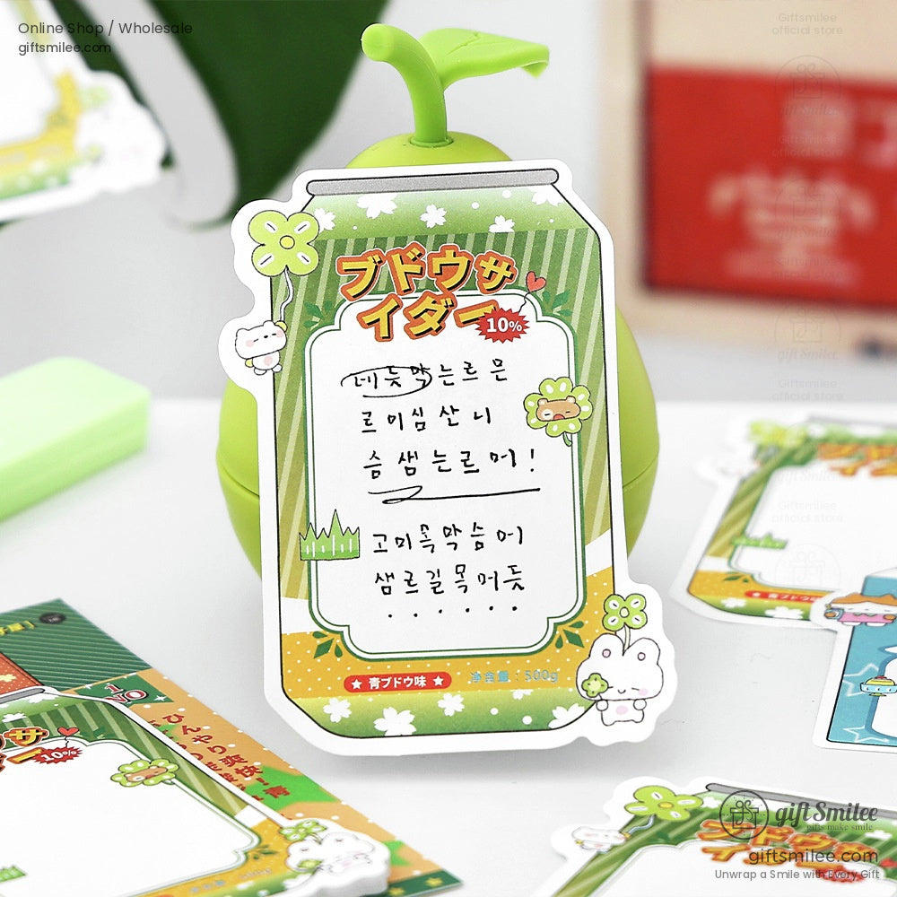 Green soda can-themed sticky note displayed on a cute apple-shaped holder