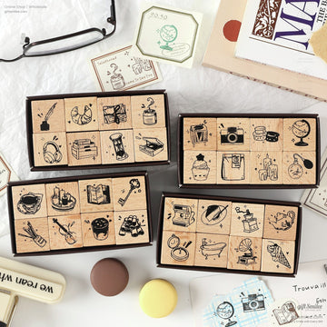 A collection of retro wooden stamps featuring daily life icons like books, globes, and cameras, displayed in elegant packaging
